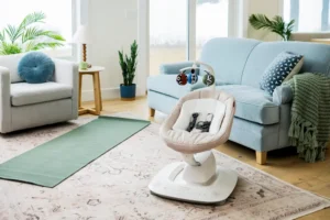 Sdraietta elettrica per neonati con struttura bianca e cuscino imbottito beige posizionata su tappeto in soggiorno luminoso