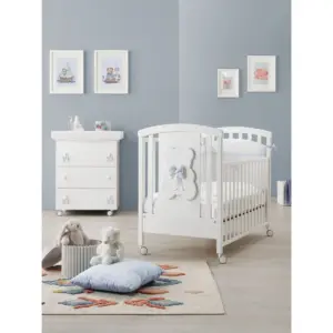 lettino bianco con decorazione orsetto e fiocco azzurro in stanza con pareti grigie e mobili bianchi