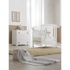 lettino bianco con decorazione a forma di orsetto e fiocco tortora in una stanza con pareti bianche e tortora