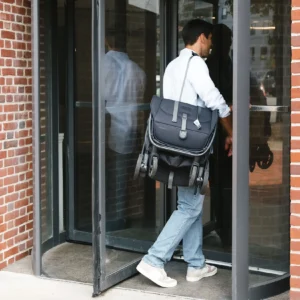 Passeggino UPPAbaby MINU V3 Jake piegato e trasportato a tracolla da un uomo
