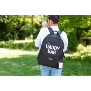 Uomo visto di spalle con zaino Daddy Bag e bambino in braccio in un parco