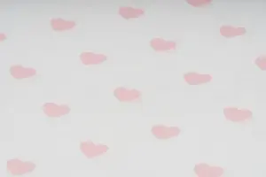 Dettaglio di tessuto con stampa di piccoli cuori rosa su sfondo chiaro